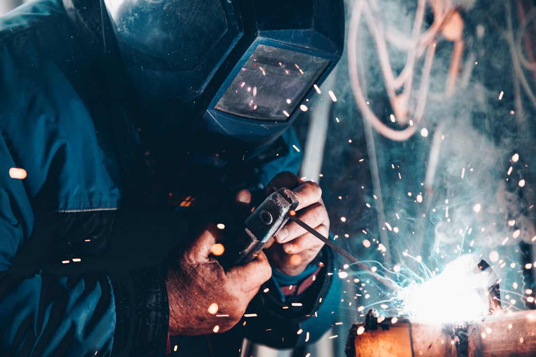 Welder at work in a dark workshop, sparks flying